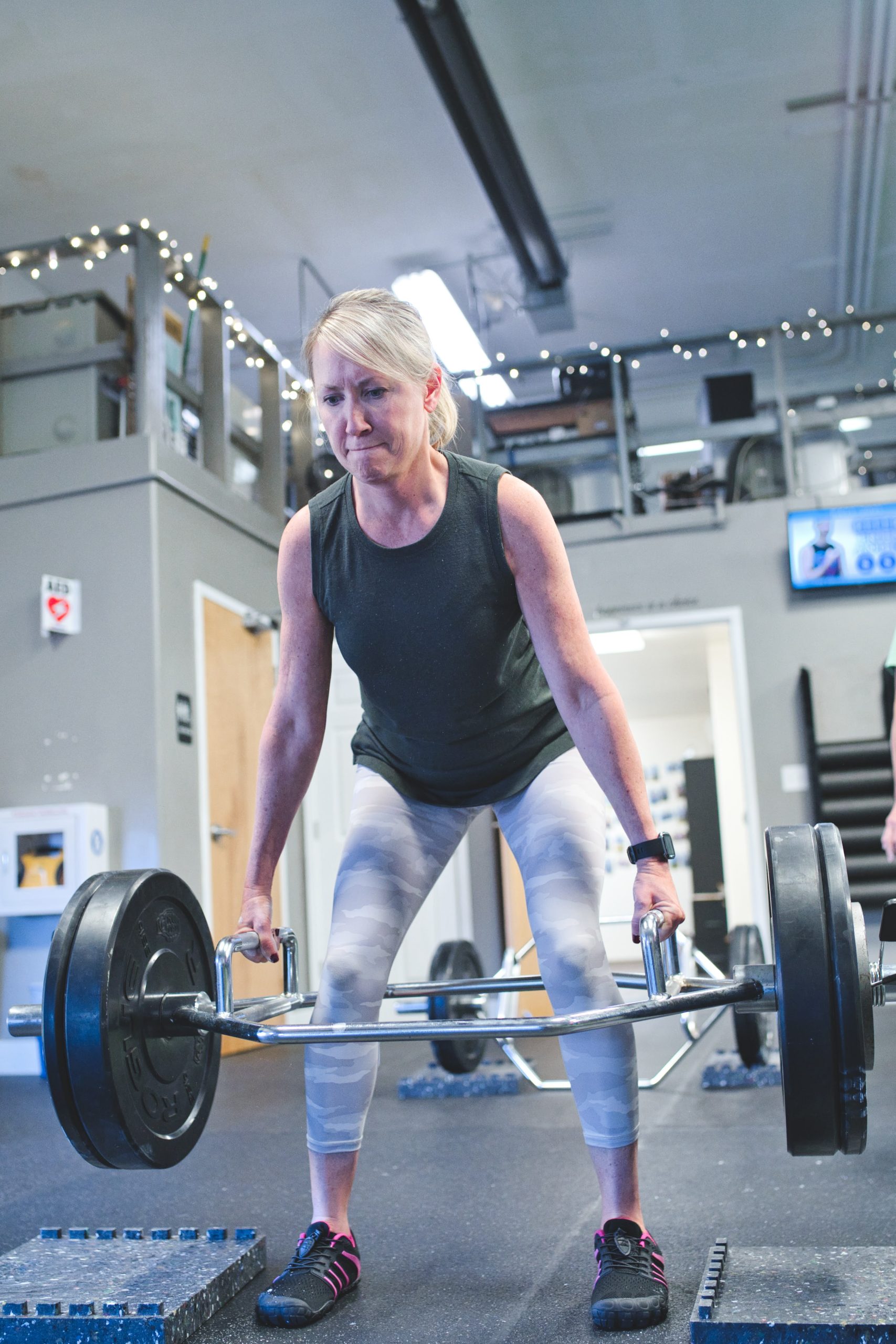 A woman doing a trap bar deadlift in a gym