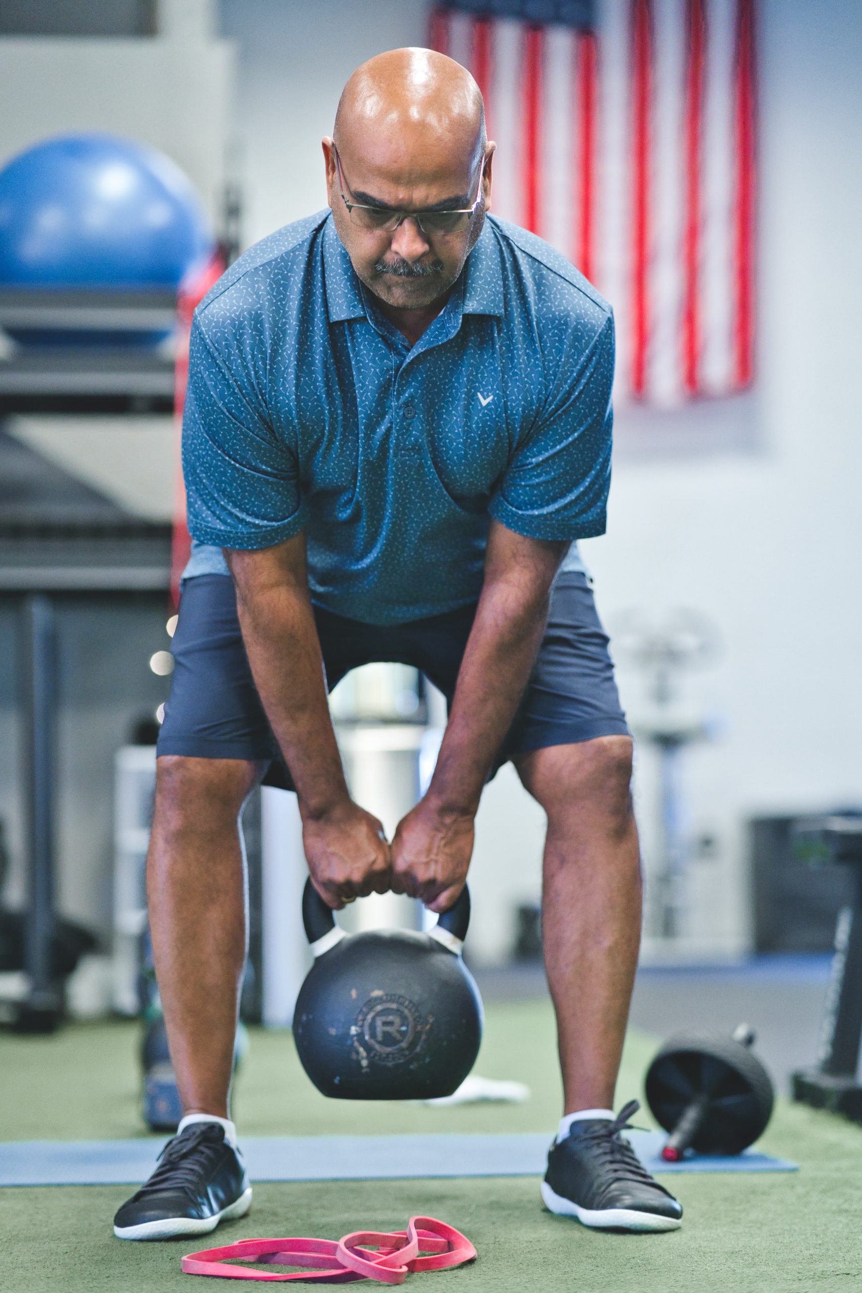 A man lifting a kettlebell in a gym