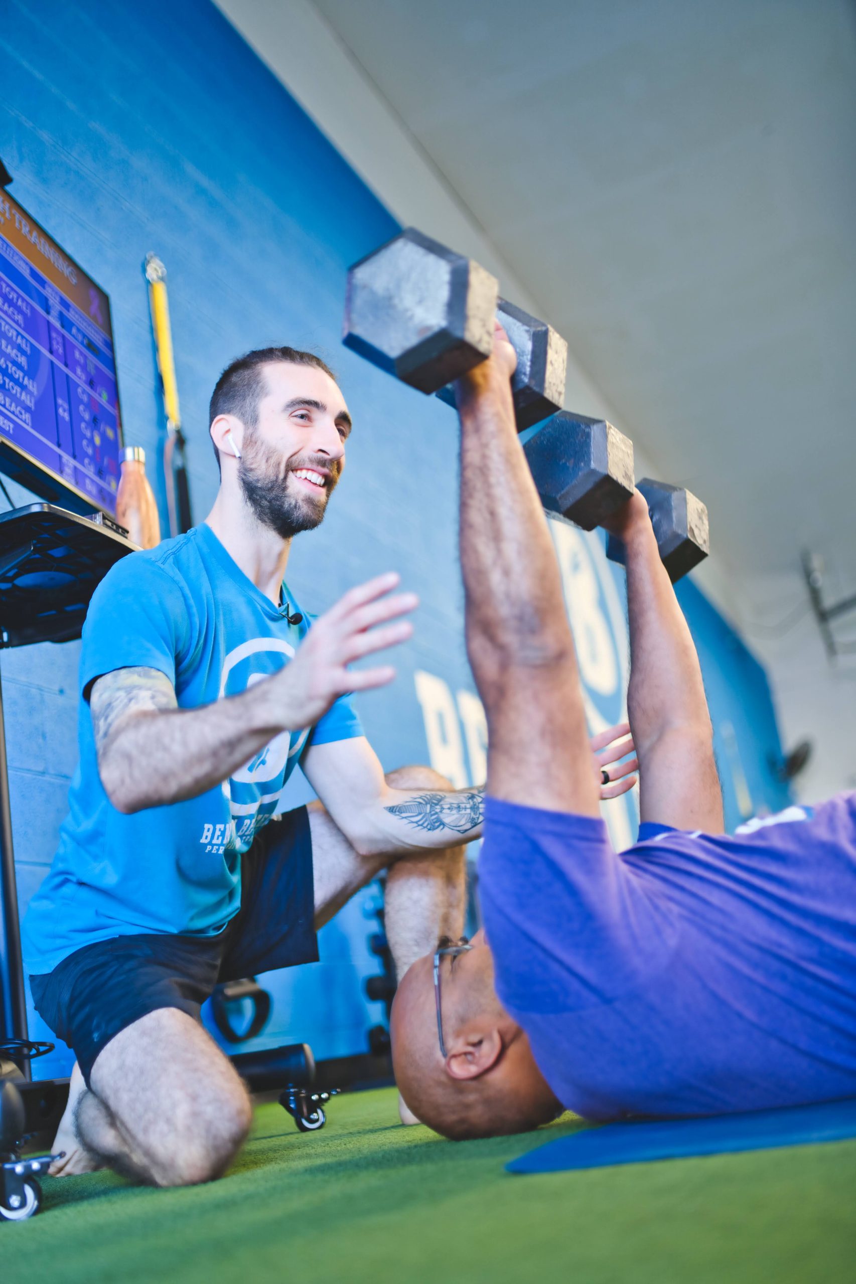 a coach spotting a member lifting dumbbells
