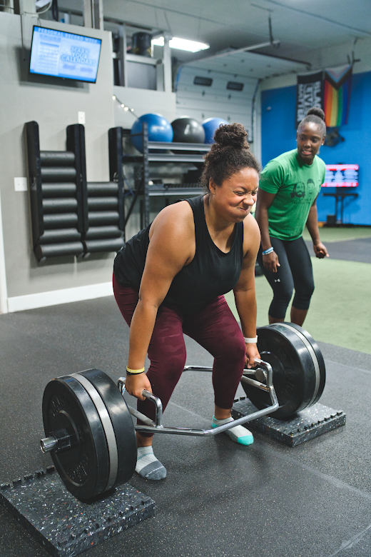 A wtrap bar deadlift in a gym with personal traineroman doing a