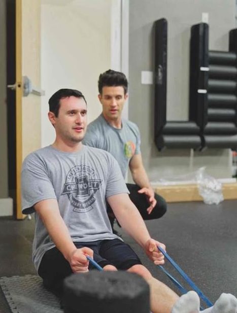 a man working out using resistance bands assisted by a personal trainer